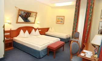 A comfortable hotel room with two beds and an elegant decor. The room has a bright atmosphere and is well-furnished with a table and chairs.