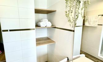 A modern bathroom with bright walls and a large mirror. Towels and plants create an inviting atmosphere.