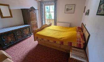 A cozy bedroom with a large bed and yellow blanket. There is a window with a view and rustic furniture.