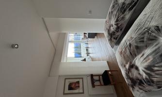 A modern bedroom with two beds and a harmonious decor. The room has large windows that allow for an outside view.