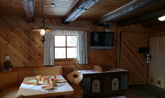 A cozy room with wooden paneling and a dining area. The table is set, and a window lets in light.