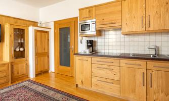 A modern kitchen with light wood cabinets and an elegant countertop. The floor is adorned with a beautiful rug.