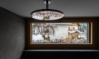A modern room with a stylish lamp and a large window. Outside, you can see snow-covered landscapes and winter plants.