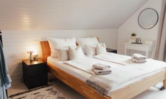 A stylish bedroom with a large bed and cozy pillows. The soft lighting and minimalist decor create an inviting atmosphere.