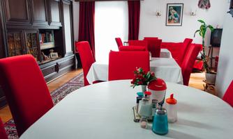 A cozy dining area with red chairs and a round table. On the table are various spice containers and a small plant.