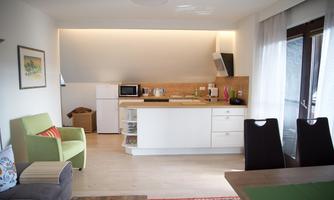 A modern kitchenette with bright furniture and a cozy living room. The room is bright and friendly, with a large window and stylish decorations.