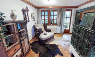 A cozy living space with a comfortable armchair and a rug made of animal hide. Large windows provide plenty of daylight and a friendly atmosphere.