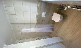 A modern bathroom with bright tiles and a shower. The decor is minimalist and designed in bright colors.
