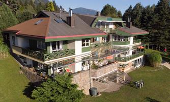 A large, modern building with multiple floors and balconies. It is situated in a green environment with trees and a well-maintained garden.