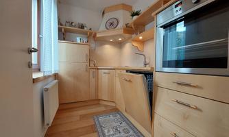 A modern kitchen with wooden cabinets and stainless steel appliances. It has a bright atmosphere and a practical layout.