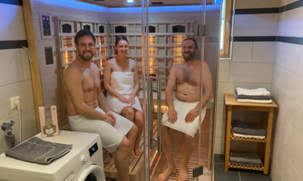 Three people are sitting in a sauna and relaxing. The environment is designed to be modern and inviting.