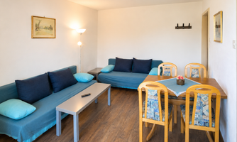 A cozy living room with foldable sofas and a dining table. The apartment is bright and friendly.