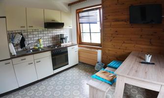 A cozy kitchen with bright cabinets and a wooden table. The room is well-lit and has a relaxed atmosphere.