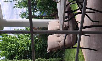 A cozy outdoor area with two beige chairs and a table. Surrounded by lush greenery and a tranquil atmosphere.