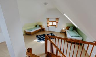 A bright room in the attic with two single beds. The walls are painted in soft colors, and a cozy carpet gives the room an inviting atmosphere.
