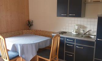 A small, cozy kitchen with a dining table and chairs. The walls are painted in warm colors, and the kitchen unit is furnished in a modern style.