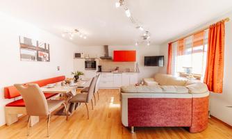 A modern apartment with an open kitchen and a cozy living area. The space is bright and friendly, with large windows and stylish furniture.