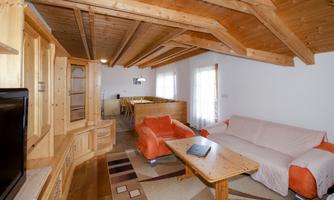 A cozy living room with a wooden ceiling and modern furniture. It is bright and welcoming, ideal for relaxing.