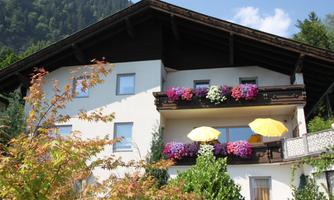 A beautiful house with balconies decorated with colorful flowers. Yellow sun umbrellas provide an inviting view of the surroundings.