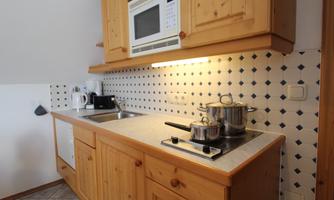 A bright kitchen with wooden cabinets and modern appliances. Pots and a microwave are on the countertop.
