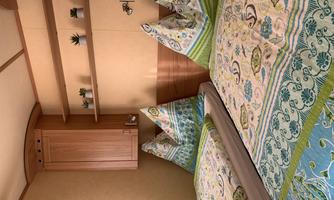 A cozy bedroom with two single beds and colorful bedspreads. On the wall, there are shelves with small plants.