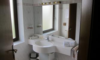 A modern bathroom with a curved sink and a large mirror. Natural light enters the room through the window.