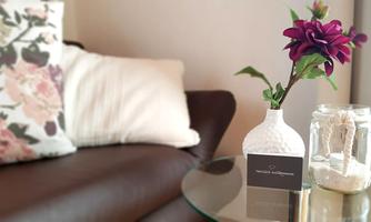 A stylish living room with a comfortable sofa and a table. On the table, there is a beautiful flower in a vase and a glass with sand.