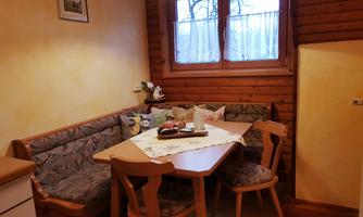 A cozy seating area with a wooden bench and a table. The light from a lamp creates an inviting atmosphere.