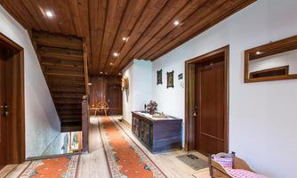 An inviting hallway with wooden paneling and a charming staircase. The floor is adorned with a traditional rug, and decorative elements hang on the walls.