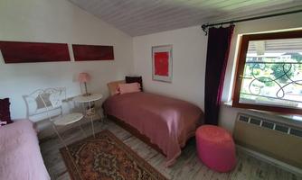 A cozy bedroom with two single beds and a beautiful window view. The walls are painted in light colors and decorated with modern artworks.