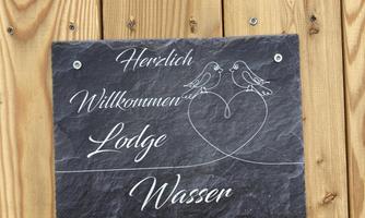 A welcome sign made of slate for a lodge by the water. It features two birds and warmly welcomes the guests.
