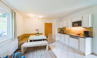 A bright and modern kitchenette with a dining table and a cozy seating area. The room is designed to be friendly and inviting.