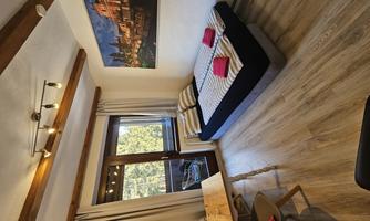 A cozy room with a double bed and a dining table. The room has large windows and a relaxing atmosphere.