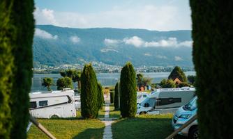A beautiful view of a campsite by the lake. In the background, there are mountains and trees visible.
