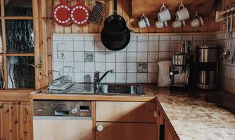 A cozy kitchen with wooden shelves and various mugs. The room has a warm atmosphere and is well-organized.