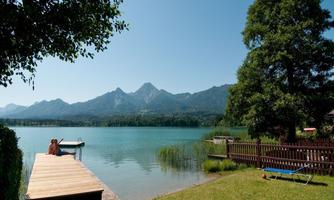 A quiet lake with mountains in the background. A wooden terrace by the water invites relaxation.