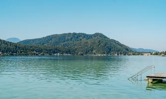 A tranquil lake surrounded by gentle hills. The sky is clear and the atmosphere is peaceful.