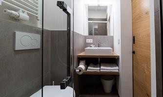 A modern bathroom with a glass shower and a sink on a wooden table. The walls are painted in neutral colors and there are fresh towels.