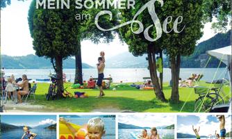 A beautiful summer day by the lake with green trees and people relaxing.  
Children are playing in the water and enjoying the warm sun.