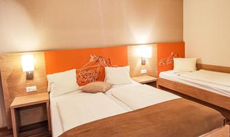 A cozy room with a double bed and a single bed. The walls are done in warm colors, and there is modern lighting.