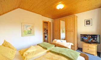 A cozy bedroom with a large double bed and bright yellow bedding. Furthermore, there is a television and a wooden wardrobe that provides nice storage space.