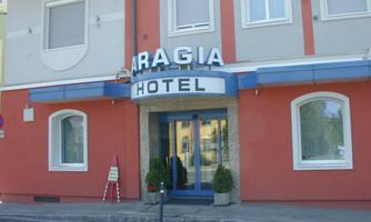 A hotel named "Aragia" stands on a street. The facade is red and has large windows.
