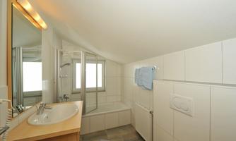 A modern bathroom with a shower and a bathtub. Bright tiles and a large mirror create a friendly atmosphere.