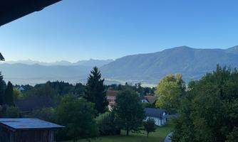 A picturesque landscape with mountains in the background and a serene village in the foreground. The sky is clear and blue, the nature is green and inviting.