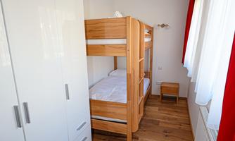 A bright room with a wooden crib and a white wardrobe. The walls are friendly and decorated with red curtains.