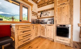A modern kitchen with wooden surfaces and an elegant oven. Large windows offer a view of the landscape.