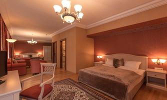 An elegant bedroom with a large bed, a chair, and a carpet. The warm colors and cozy decor create an inviting atmosphere.