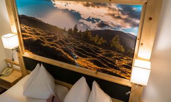 A cozy bedroom with a large mural of a picturesque landscape. Soft light falls on the pillows, creating a relaxed atmosphere.
