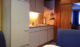 A small, cozy kitchen with modern appliances and warm lighting. The space is well-organized and inviting.