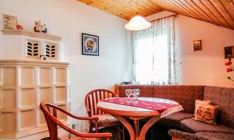 A cozy eat-in kitchen with a wooden table, chairs, and a wooden ceiling. The windows let in plenty of light and create an inviting atmosphere.